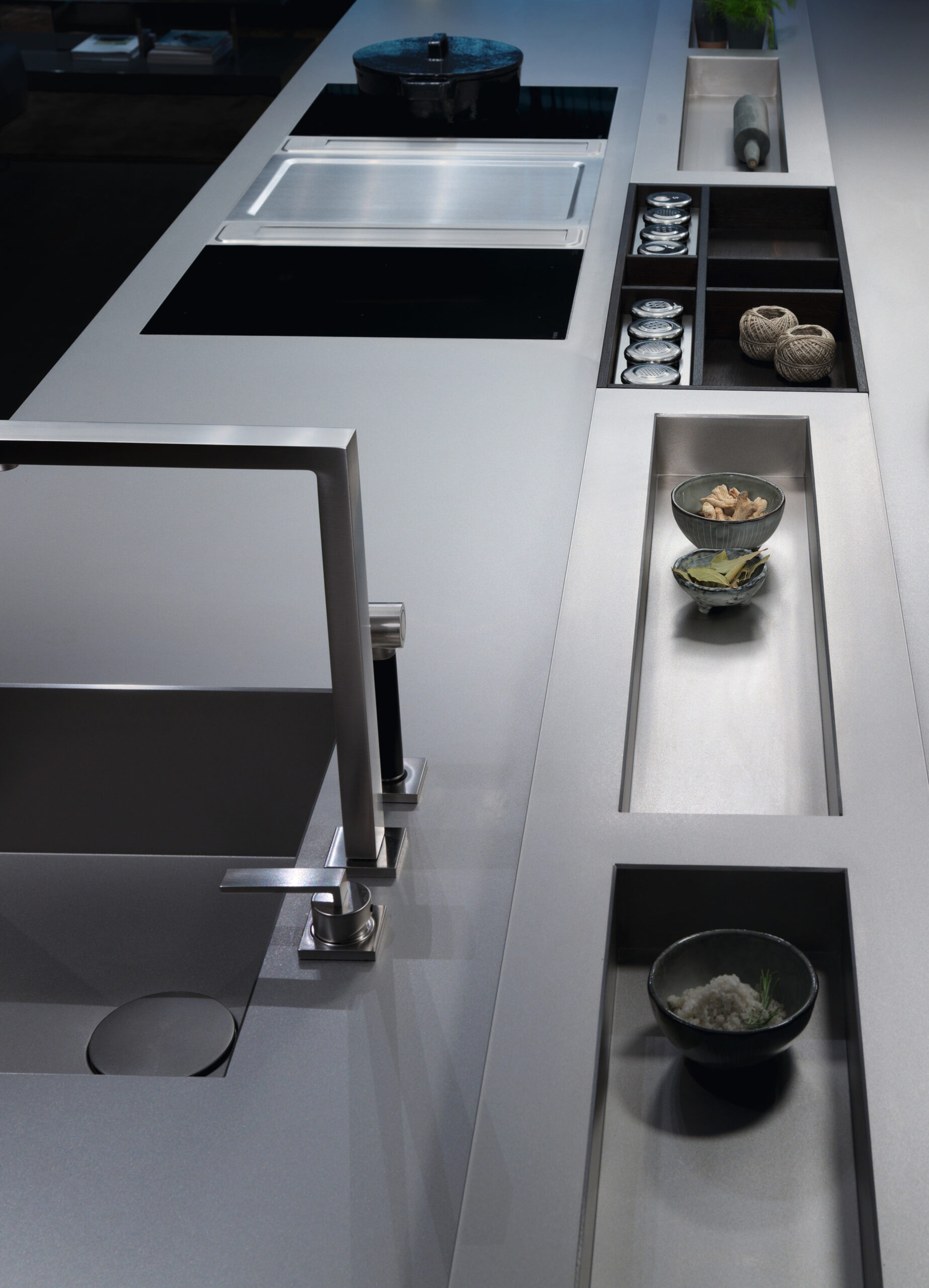 Moderne Küchenzeile mit Edelstahl-Arbeitsfläche, eingebautem Kochfeld und offenen Regalfächern mit Küchenutensilien