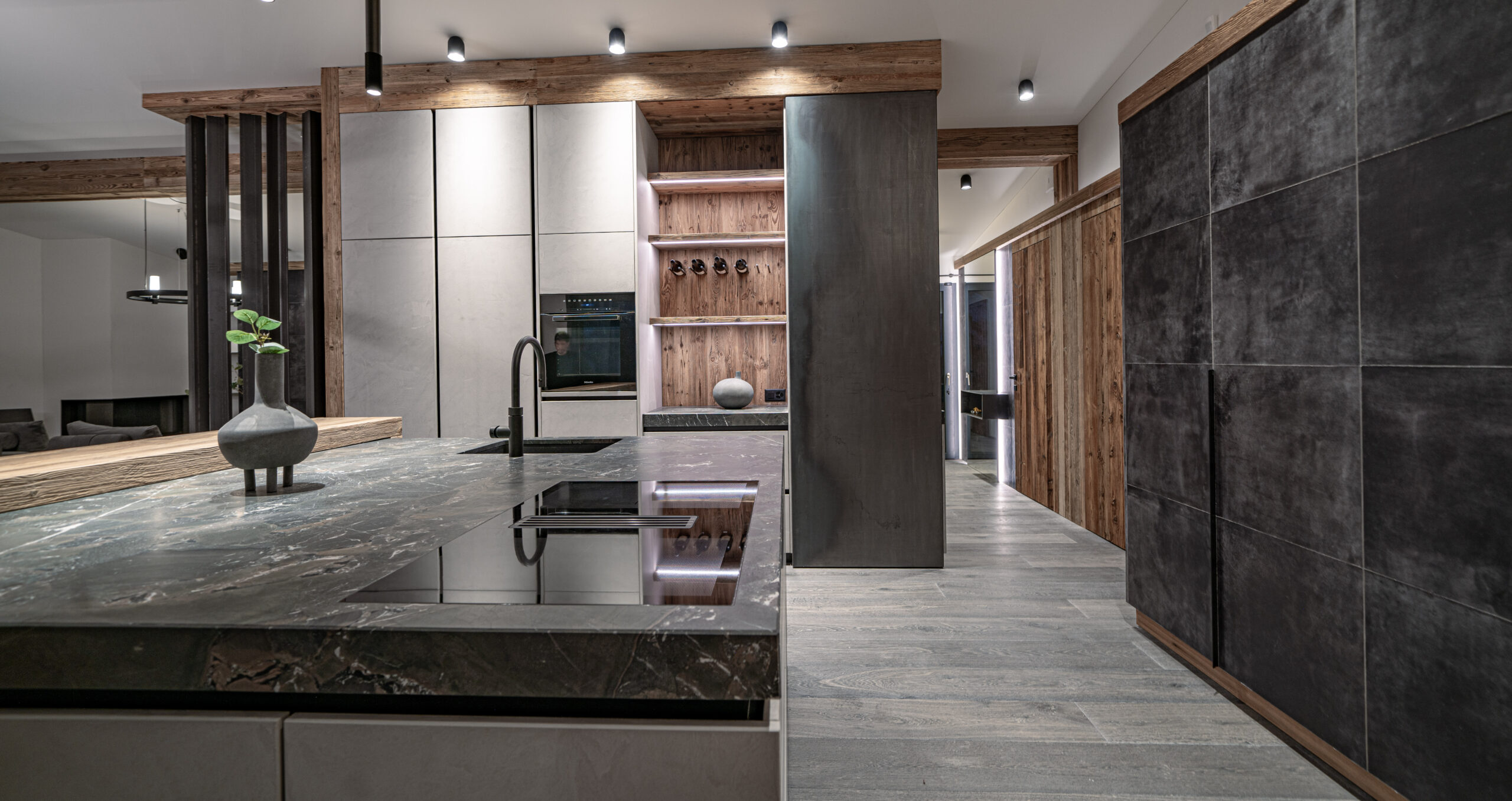 Luxuriöse Küche mit Granitarbeitsplatte, Holzelementen und modernen Einbaugeräten, beleuchtet durch eingebaute Deckenspots